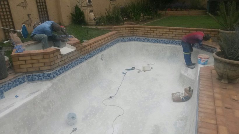 Team re-tiling the waterline in blue mosaic