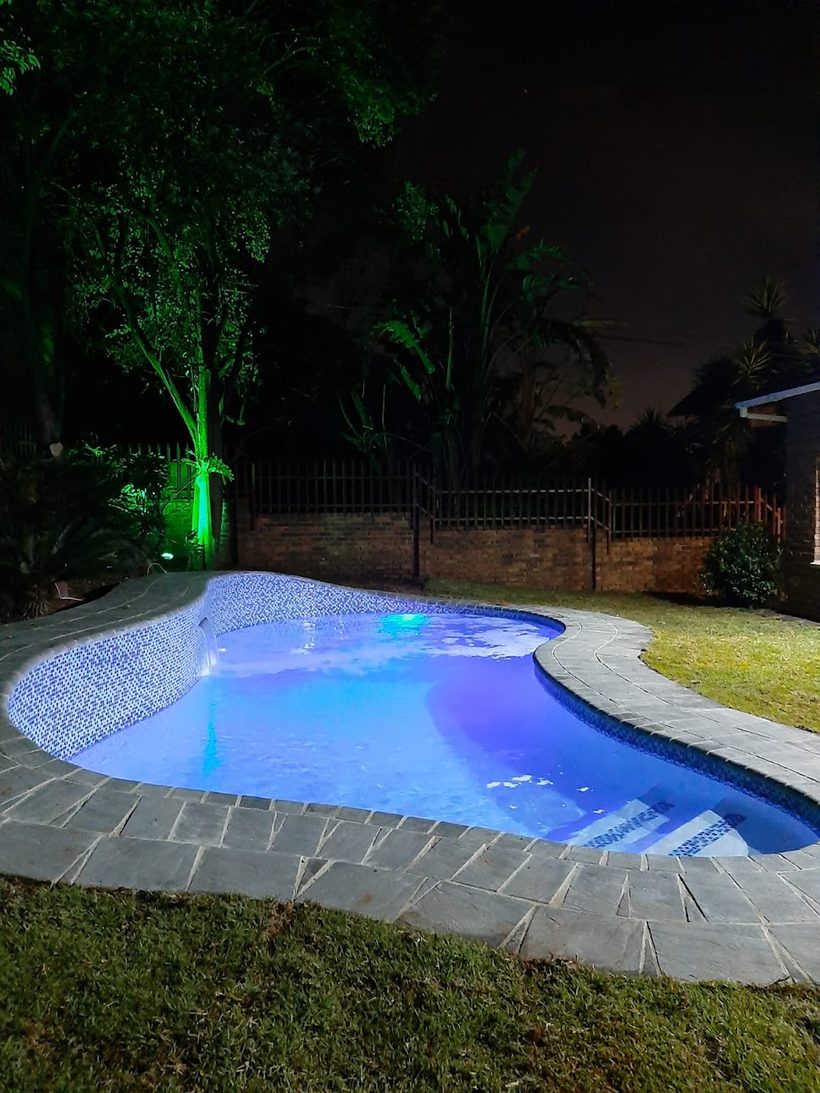 The finished pool at night, lit blue, with new mosaic waterline and slate surround