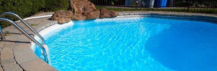 A pool with an installed rock waterfall feature